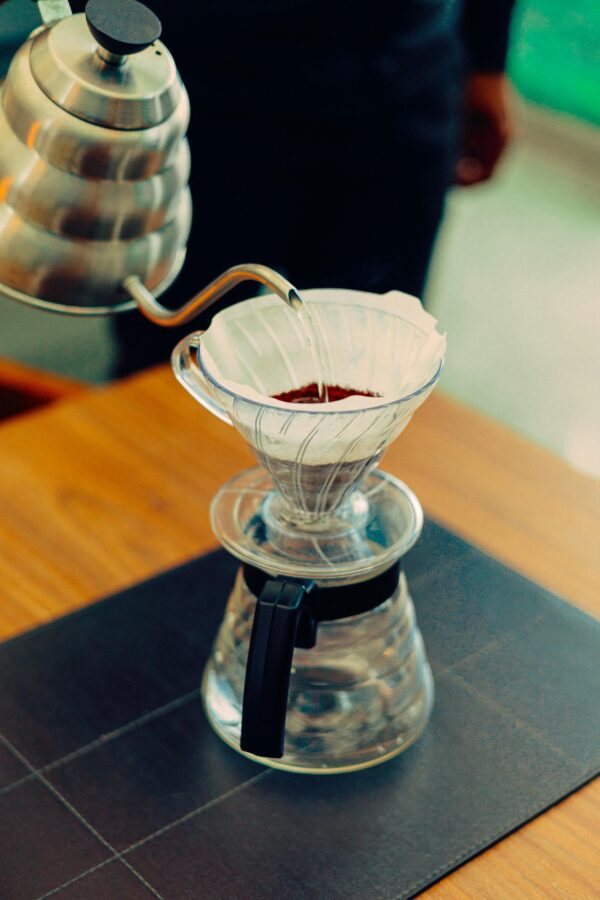 Close-up of a pour-over coffee maker with hot water being poured through a filter for fresh coffee brewing.